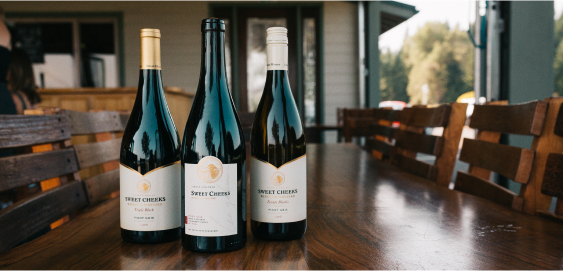 Three bottles of Sweet Cheeks Winery's club-exclusive wines on a table.