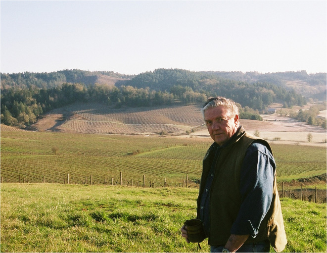 Founder, Dan Smith, holding a cup of coffee, overlooking the vineyard.