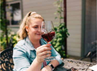 Woman holding a glass of red wine and swirling it.