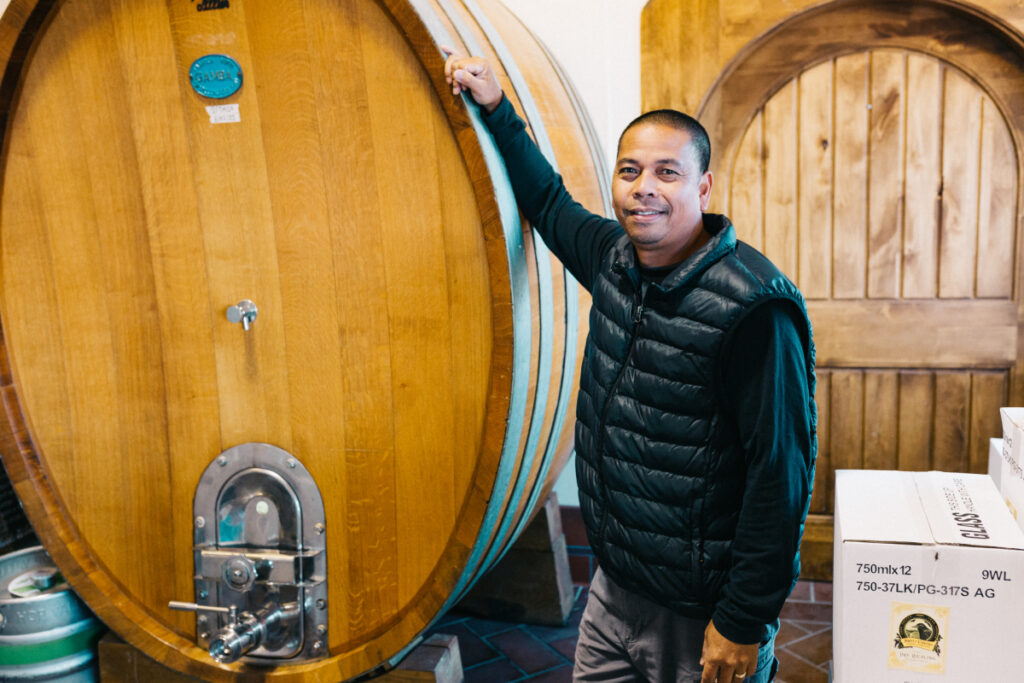 Sweet Cheeks winemaker posing against an oak wine barrel