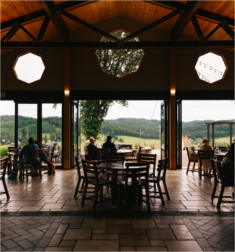 Photo of the vista room patio with people at the tables, looking out to the valley view. 
